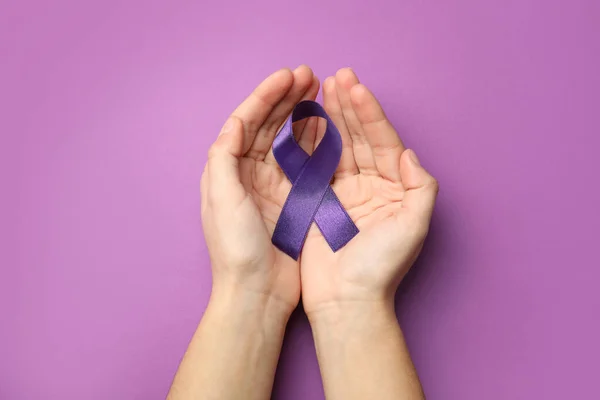 Vrouw met paars lint op lila achtergrond, bovenaanzicht. Bewustmaking huiselijk geweld — Stockfoto