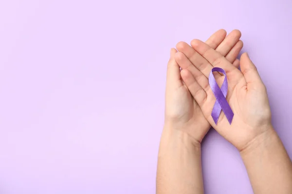 Mujer sosteniendo cinta púrpura sobre fondo lila, vista superior con espacio para texto. Sensibilización sobre violencia doméstica — Foto de Stock