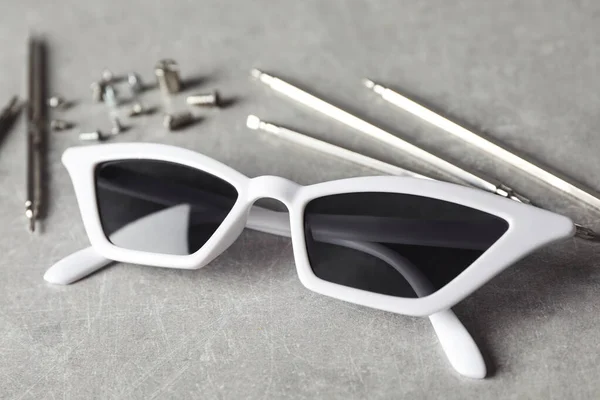 Elegantes gafas de sol femeninas y herramientas de fijación en mesa gris — Foto de Stock