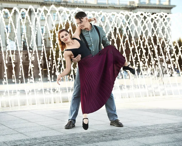 Hermosa pareja joven practicando movimientos de baile cerca de la fuente al aire libre — Foto de Stock