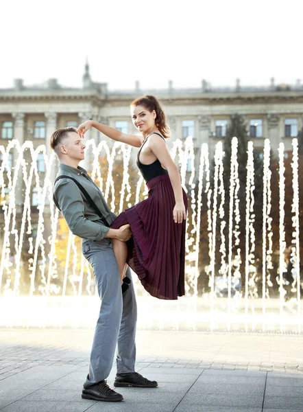 Hermosa pareja joven practicando movimientos de baile cerca de la fuente al aire libre — Foto de Stock