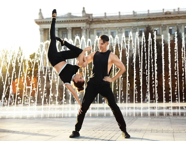 Hermosa pareja joven practicando movimientos de baile cerca de la fuente al aire libre — Foto de Stock