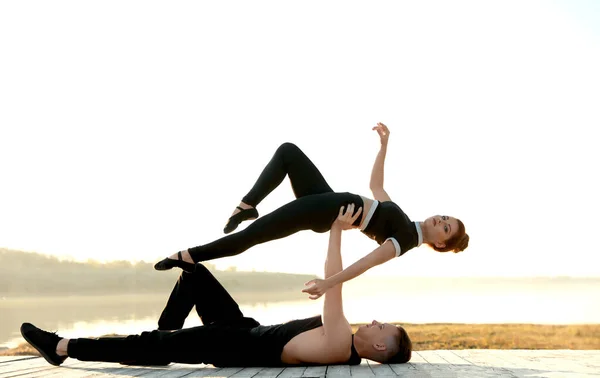 Hermosa pareja joven practicando movimientos de baile cerca del río al atardecer — Foto de Stock