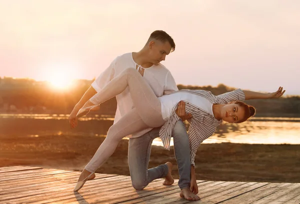 Mooi jong paar oefenen dans beweegt in de buurt van rivier bij zonsondergang — Stockfoto