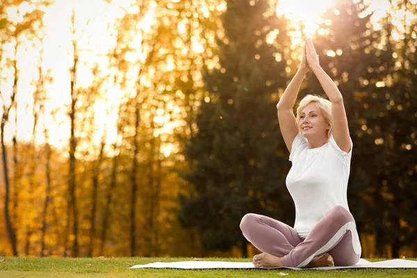 Happy mature woman practicing yoga in park. Active lifestyle — Stock Photo, Image