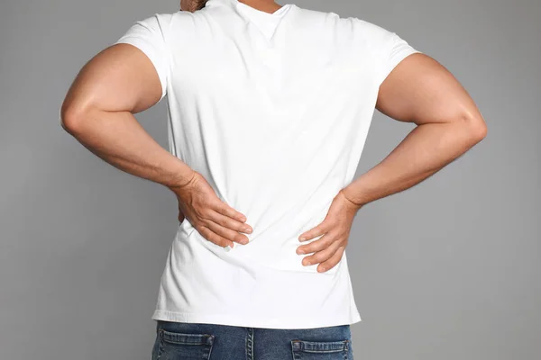 Hombre que sufre de dolor de espalda sobre fondo gris claro, primer plano —  Fotos de Stock