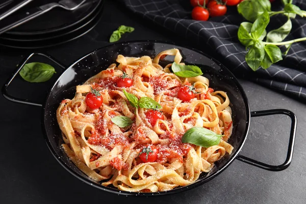 Leckere Pasta mit Tomaten, Käse und Basilikum auf schwarzem Tisch — Stockfoto