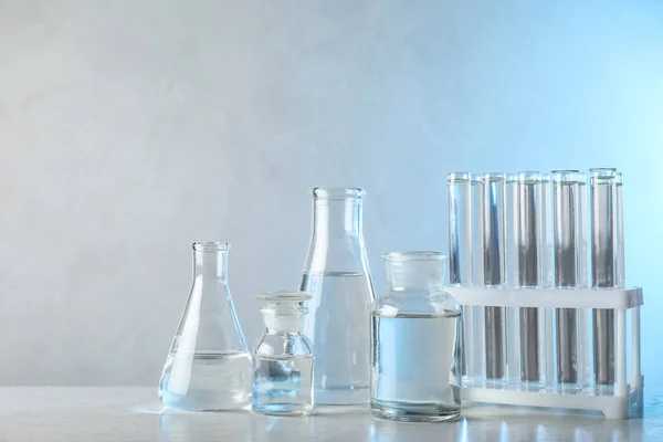 파란 배경에 대한 분석을 위해 표에 액체 샘플을 담은 실험실 유리 제품 — 스톡 사진