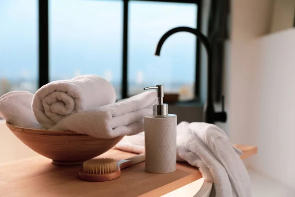 Clean towels, soap dispenser and shower brush in bathroom — Stock Photo, Image