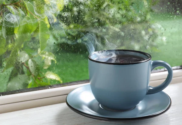 Une tasse de boisson chaude sur le rebord de la fenêtre. Météo pluvieuse — Photo
