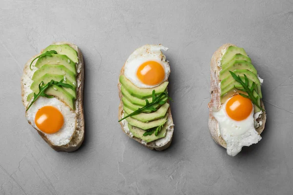 Läckra avokadomackor på grått bord, platt ligg — Stockfoto