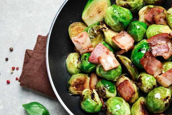 Délicieux choux de Bruxelles avec bacon dans une casserole sur une table lumineuse, gros plan — Photo