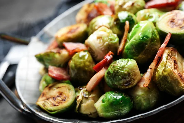 Heerlijke spruitjes met spek in schotel op tafel, close-up — Stockfoto