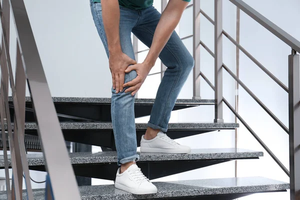 Mężczyzna cierpiący na ból kolana schodzący na dół, zbliżenie. Problemy zdrowotne — Zdjęcie stockowe