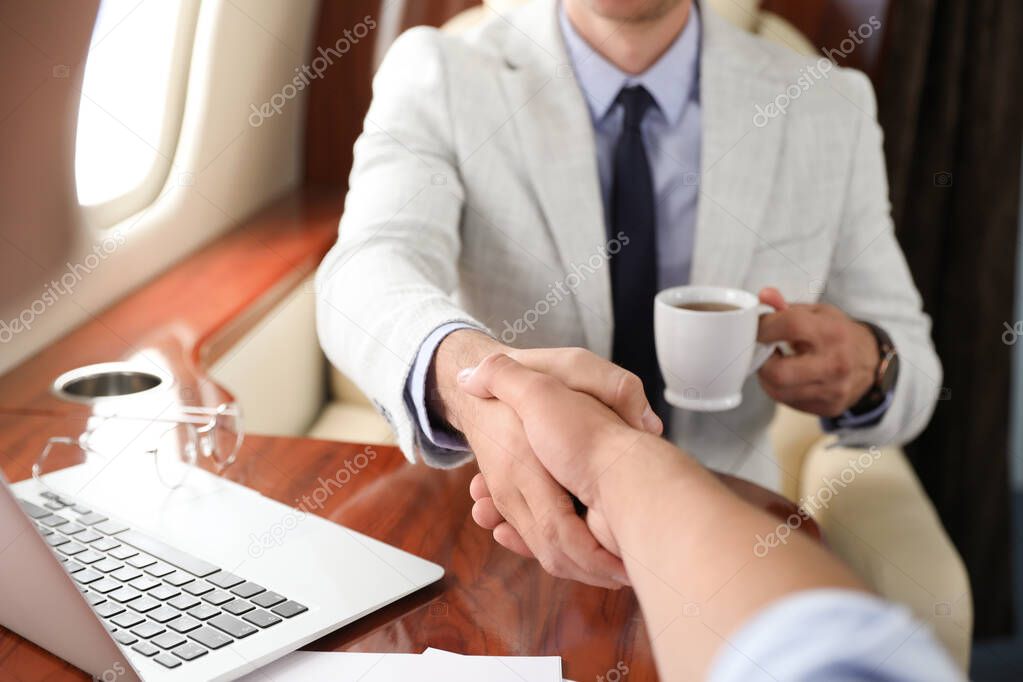 Young people shaking hands after bargaining on plane, closeup. Business deal