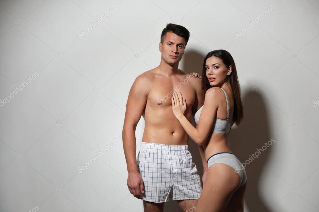 Açık gri arka planda iç çamaşırı giyen genç çift, mesaj için yer