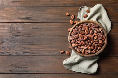 Tahta masanın üstünde kakao çekirdeği olan bir kase, en iyi manzara. Metin için boşluk