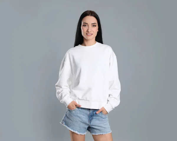 Портрет молодой женщины в свитере на сером фоне. Задумайтесь над дизайном — стоковое фото
