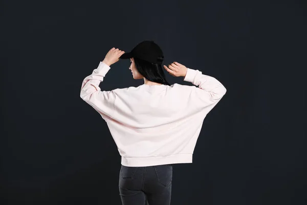 黒を背景にセーターを着た若い女性。デザインのためのモック — ストック写真