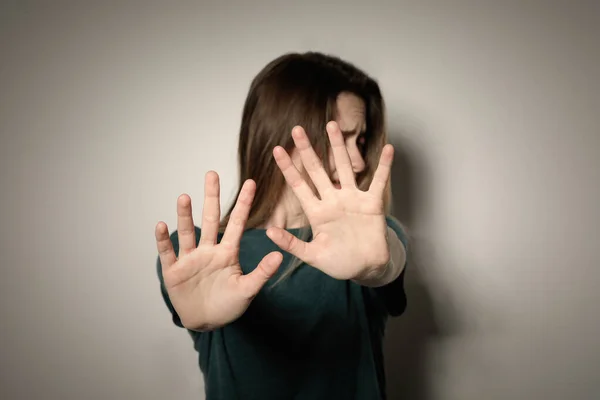 Mujer joven haciendo gesto de parada contra fondo claro, enfoque en la mano — Foto de Stock
