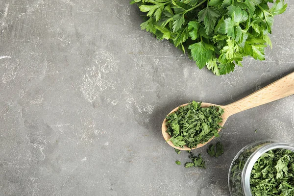 Flat lay composition with fresh and dried parsley on grey stone table. Space for text