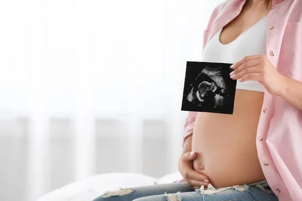 Pregnant woman with ultrasound picture indoors, closeup. Space for text — Stock Photo, Image