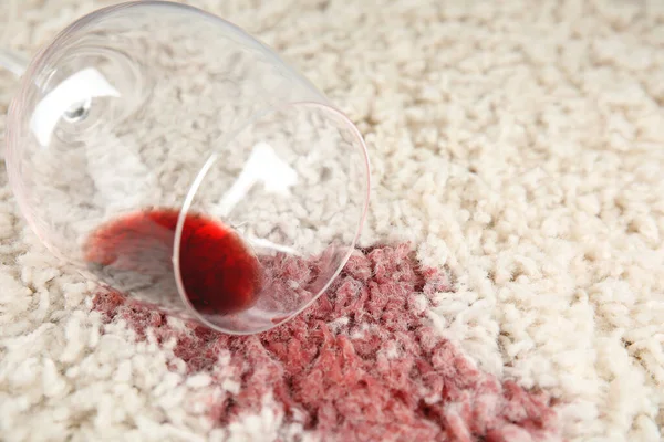 Overturned glass and spilled exquisite red wine on soft carpet, closeup. Space for text — Stock Photo, Image