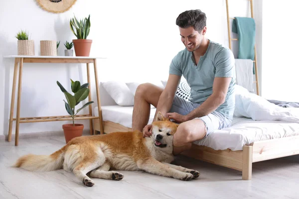Hombre y Akita Inu perro en el dormitorio decorado con plantas de interior — Foto de Stock
