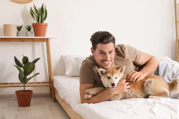 Uomo e Akita Inu cane in camera da letto decorato con piante d'appartamento — Foto Stock