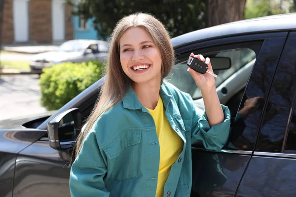 Νεαρή γυναίκα με κλειδί κοντά στο νέο αυτοκίνητο σε εξωτερικούς χώρους — Φωτογραφία Αρχείου