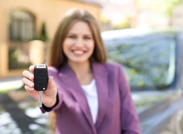 Молодая женщина с ключом рядом с новым автомобилем на открытом воздухе, сосредоточиться на руку — стоковое фото