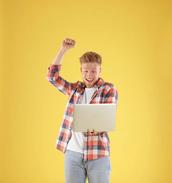 Homem emocional com laptop no fundo amarelo — Fotografia de Stock