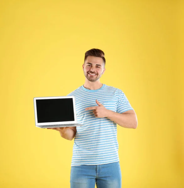 Homme heureux avec ordinateur portable sur fond jaune. Espace pour le texte — Photo