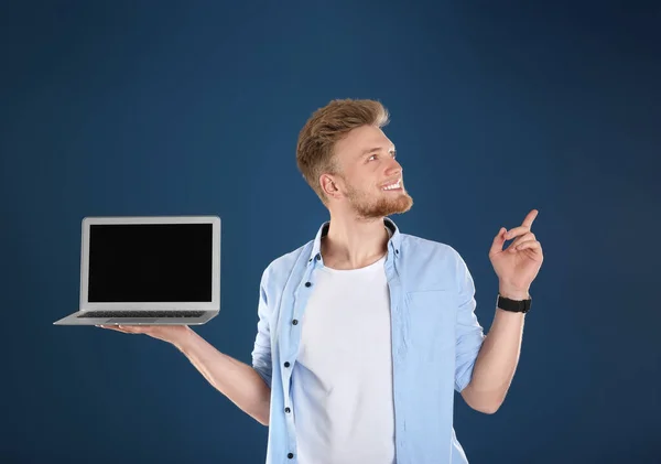 Happy man with laptop on blue background. Space for text