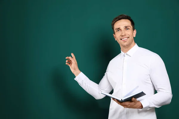 Porträt eines männlichen Lehrers mit Buch auf farbigem Hintergrund. Raum für Text — Stockfoto