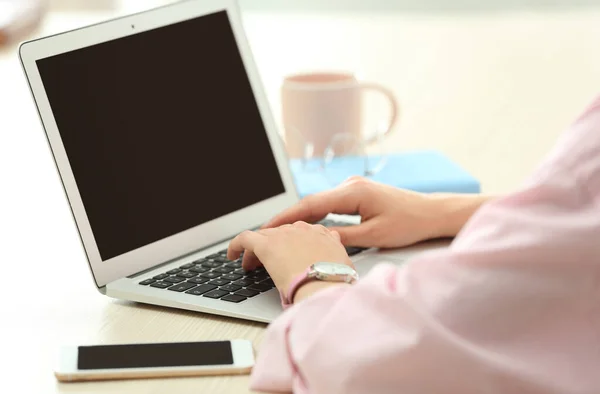 Молода жінка використовує ноутбук за столом в приміщенні, крупним планом з місцем для тексту — стокове фото