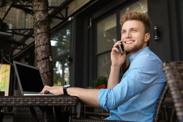 Dışarıdaki kafede oturan laptoplu yakışıklı genç adam. — Stok fotoğraf