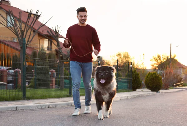 Jovem andando seu cão pastor caucasiano ao ar livre — Fotografia de Stock