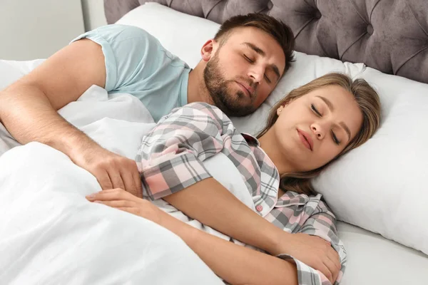 Pareja joven durmiendo juntos en la cama en casa —  Fotos de Stock