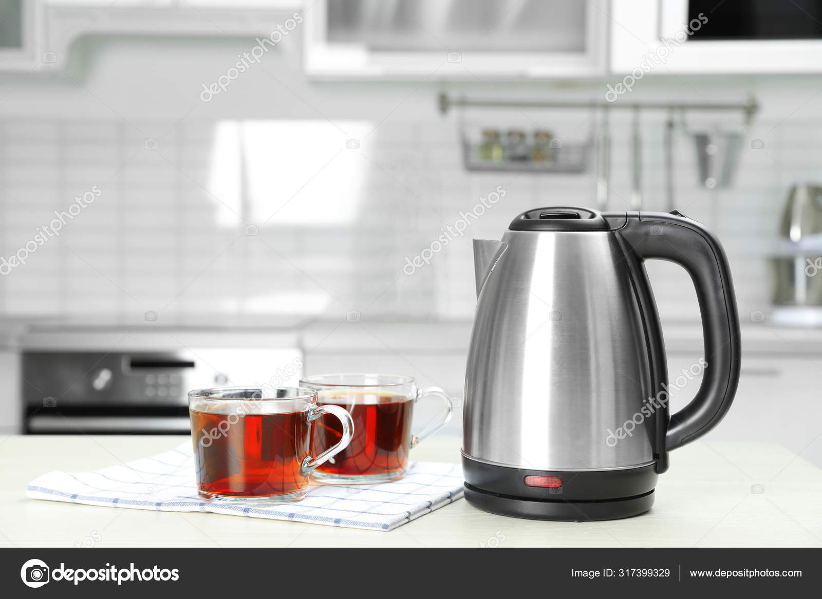 Modern electric kettle and cups of tea on white wooden table in kitchen.  Space for text Stock Photo by ©NewAfrica 317399329