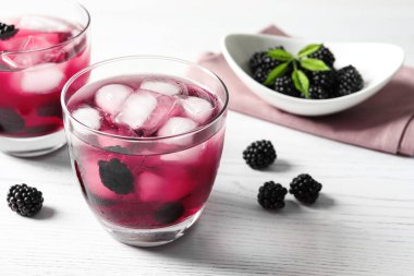 Beyaz ahşap masada lezzetli, ferahlatıcı böğürtlen limonatası.