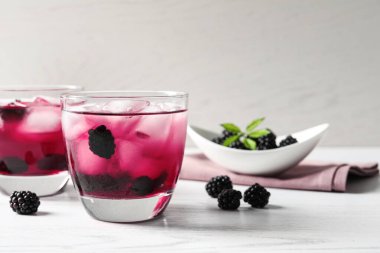 Beyaz ahşap masada lezzetli, ferahlatıcı böğürtlen limonatası.