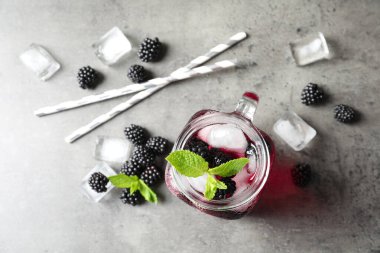 Gri masada böğürtlen kavanozu ve limonata ile düz kompozisyon