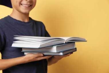 Küçük çocuk sarı arka planda kitap okuyor, yakın plan.