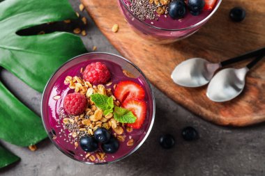 Granola ve böğürtlenli lezzetli acai tatlıları gri masada servis edilir. Metin için boşluk