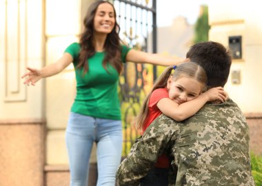 Askeri üniformalı bir adam ve ailesi dışarıda.