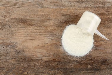 Tahta masadaki protein tozuyla ters çevrilmiş ölçüm kepçesi, üst manzara. Metin için boşluk