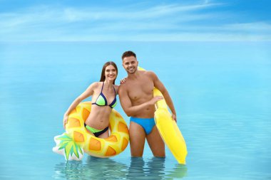 Bikinili genç bir kadın ve plajda şişme oyuncakları olan erkek arkadaşı. Hoş bir çift.