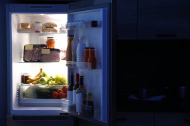 Geceleri mutfakta ürünlerle dolu açık buzdolabı