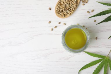 Kenevir kremi kavanozu ve tohumlar beyaz ahşap masa üzerinde, düzlük ve metin için yer var. Organik Kozmetik
